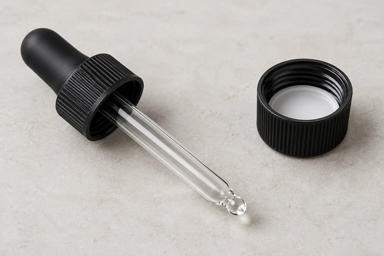 Glass pipette and bulb assembly beside a separate plain screw cap