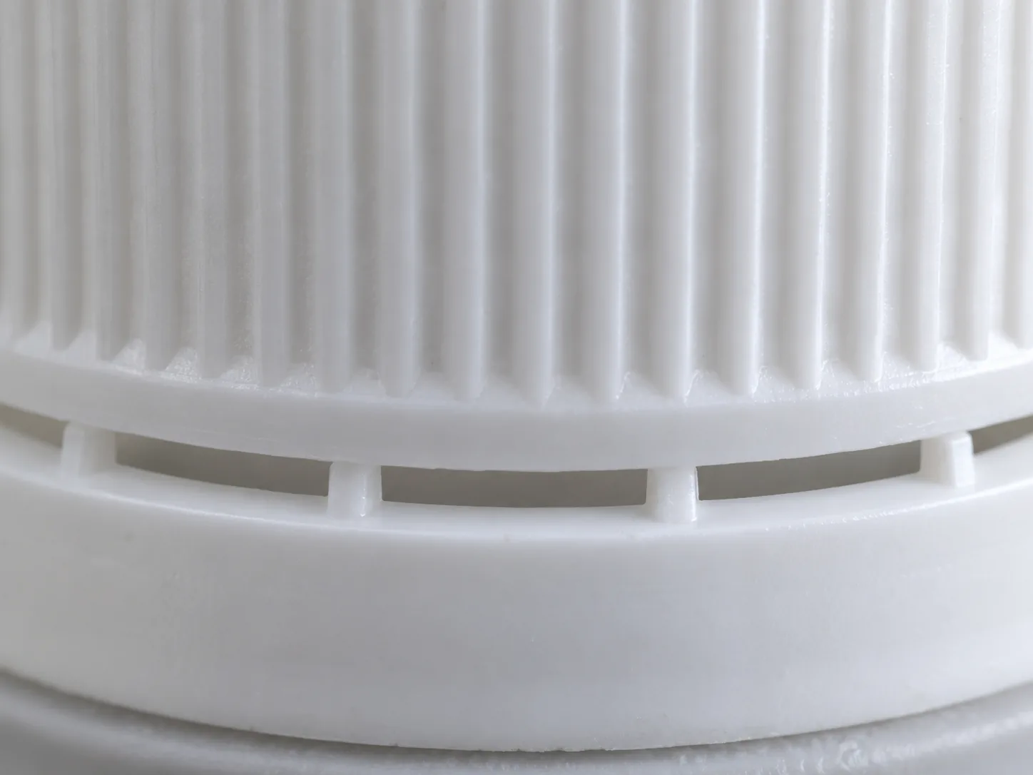 Close view of intact plastic bridges between a white cap shell and its tamper band